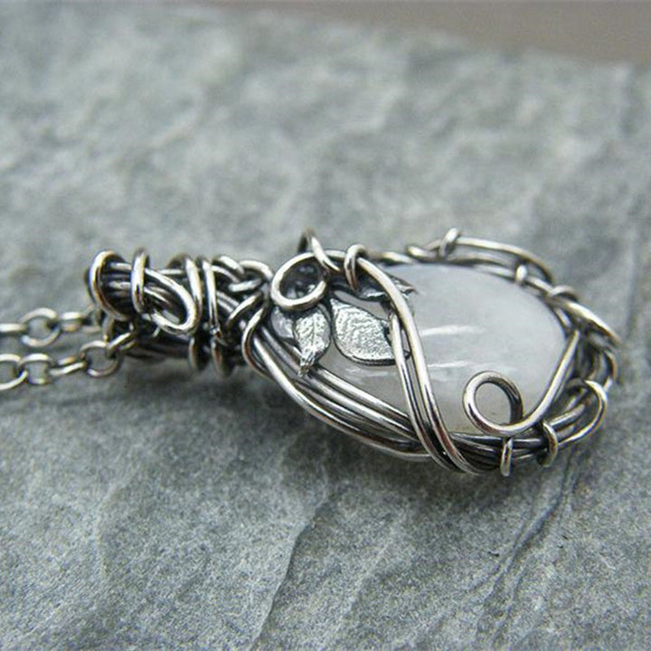 Frau trägt elegante Retro Mondstein Halskette in Tropfenform. Stilvolle Vintage Kette für Damen, zeitloser Edelsteinschmuck.
