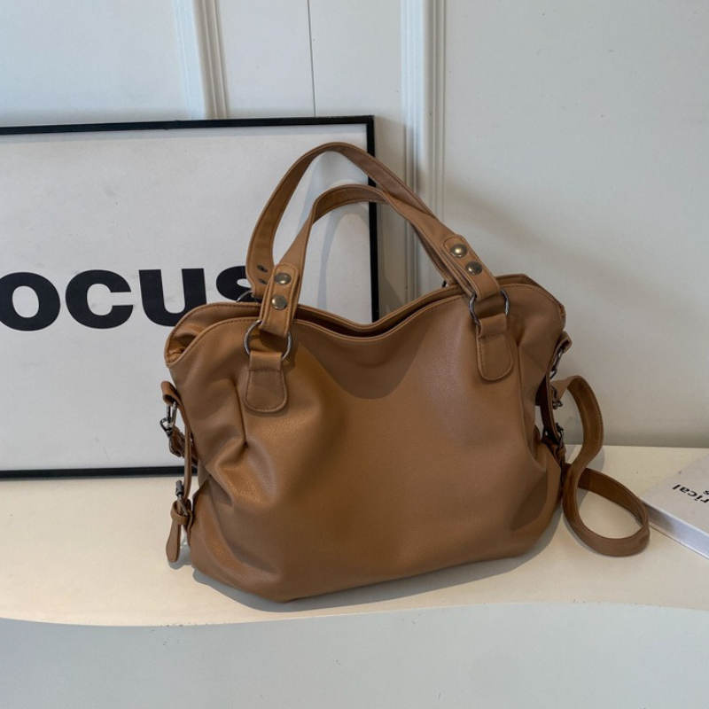 Frau trägt elegante, schwarze Tragetasche als Schultertasche. Vielseitiges Damenaccessoire.