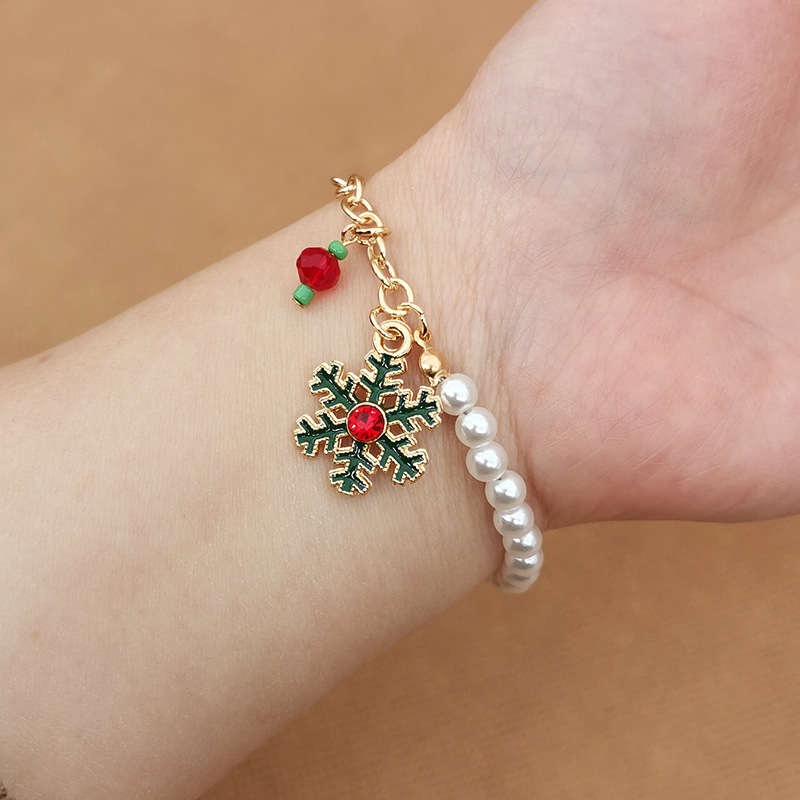 Detailansicht: Damen Charm-Armband mit glänzenden Perlen, Schneeflocken & Weihnachtsmann-Anhängern.