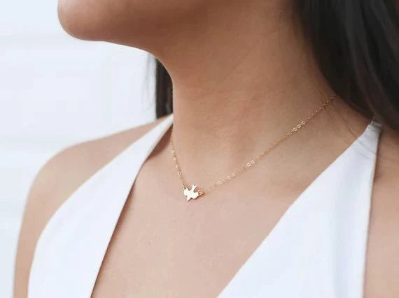 Stilvolle Damenhalskette mit kleinem fliegendem Vogel-Anhänger, filigraner Schmuck als Glücksbringer.