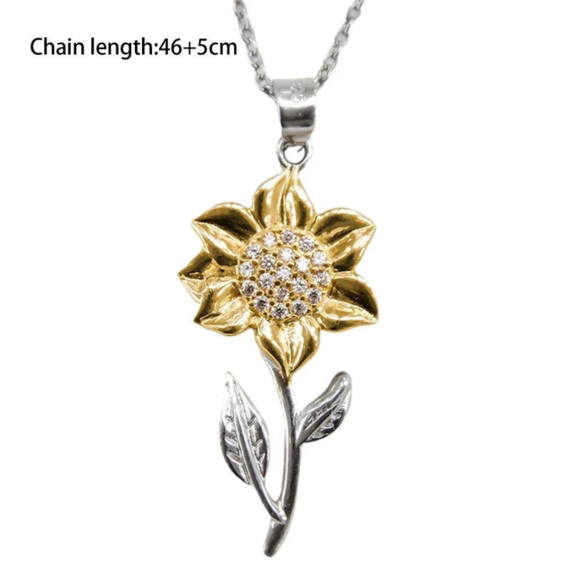 Nahaufnahme einer goldenen Sonnenblumenkette mit präzisem Kristall in der Mitte des Anhängers.