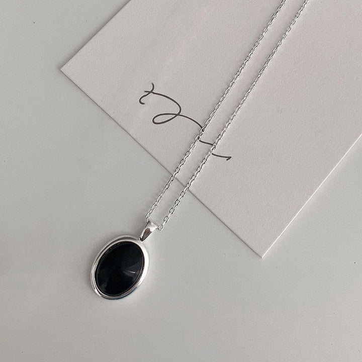 Damen trägt minimalistische schwarze Opal-Halskette aus S925 Silber, ovaler Edelstein, elegant.