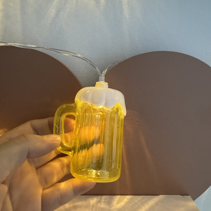 Nahaufnahme eines beleuchteten LED-Bierkrugs an der Lichterkette, detailreiche Party-Deko.