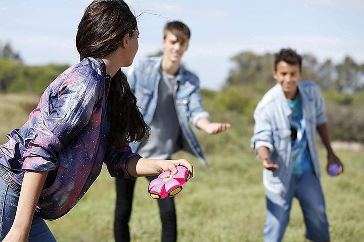 Blauer Verwandlungsball im Gras: Der Outdoor Scheibenball liegt bereit für abwechslungsreiches Spiel auf dem Spielplatz.