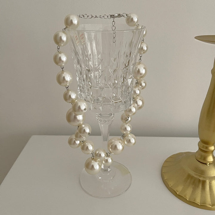 Damen Perlenkette am Hals einer Frau, eleganter Perlenschmuck, klassisches Accessoire für Abendgarderobe.