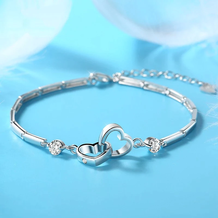 Damen Silberarmband mit Doppelherz-Motiv am Handgelenk getragen; elegantes Schmuckstück, perfektes Geschenk.