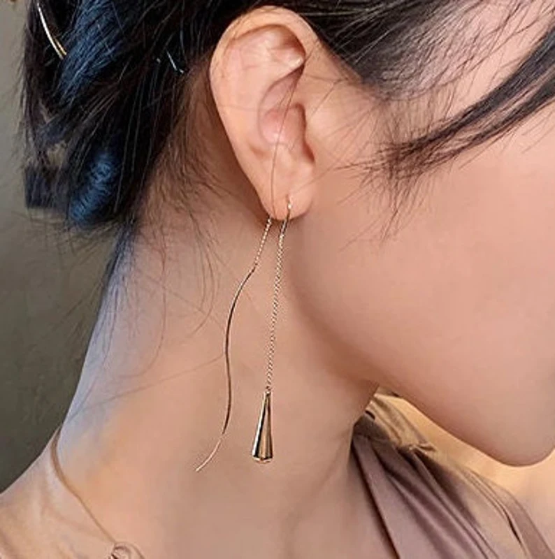 Nahaufnahme: Filigrane goldene Wassertropfen-Ohrringe, minimalistischer Damenschmuck aus Legierung.