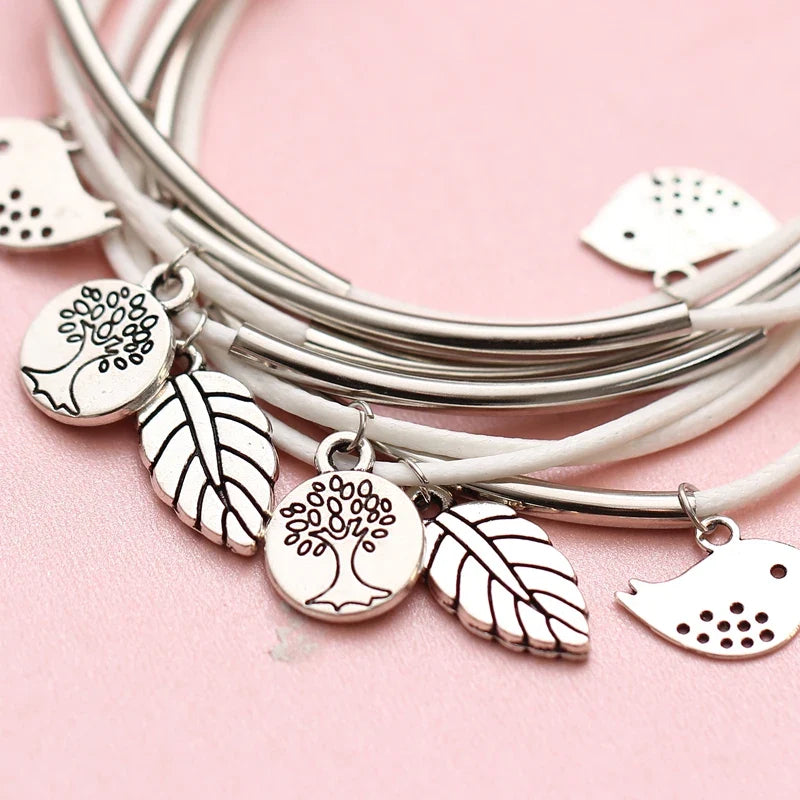 Accessoire: Mehrschichtiges Armband mit Blatt- und Vogel-Anhängern.