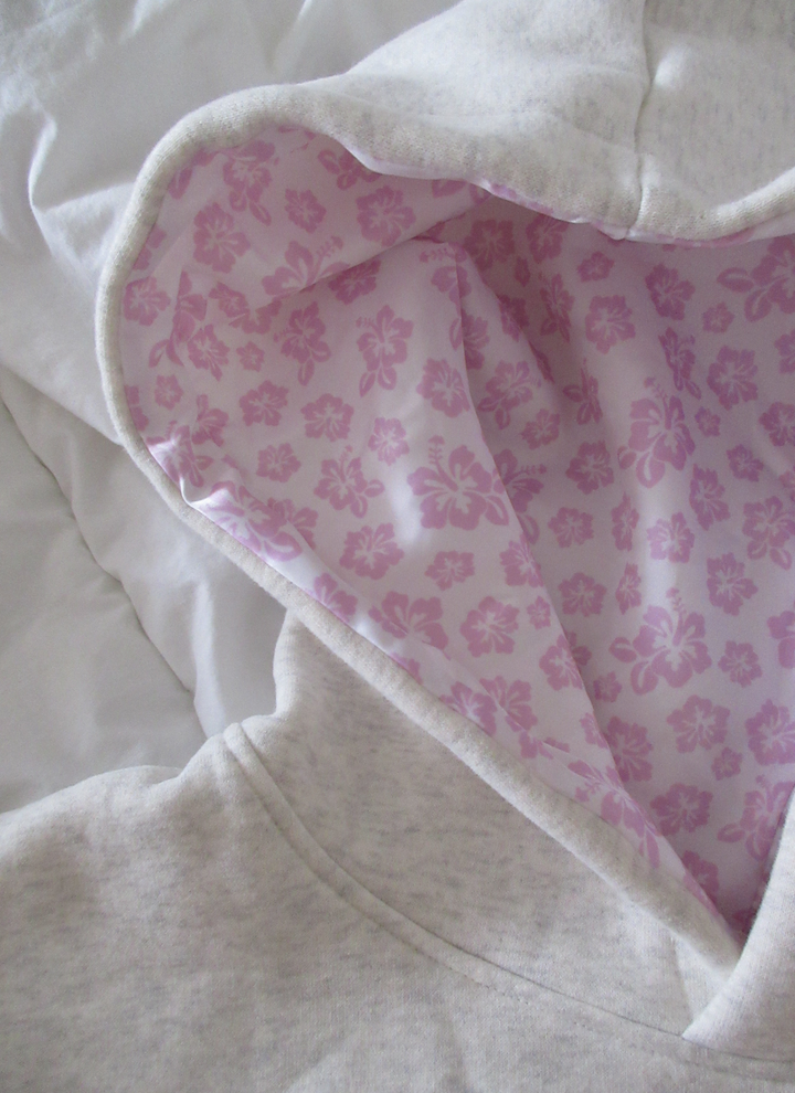 Frau trägt wärmenden Damen Hibiskus Kapuzenpullover. Floral bedruckter Hoodie für stilvolle Herbst- & Wintermode.