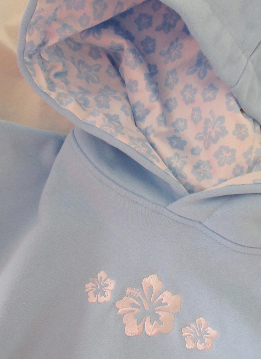 Moderner Damen Hoodie mit Hibiskusblüten, Kapuzenpullover in Rosé/Himmelblau. Vielseitige Damenbekleidung für Streetwear.