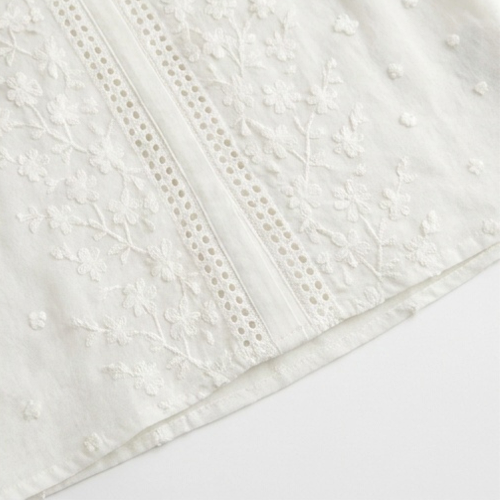 Weiße Damenbluse mit floraler Stickerei und verdeckter Knopfleiste, modernes Design für Damen.