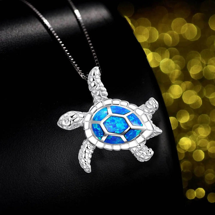 Nahaufnahme einer silbernen Schildkröten-Halskette mit funkelndem Opal als Panzer. Hochwertiger Damenschmuck.