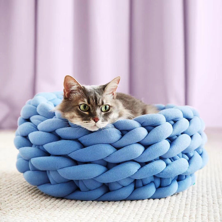 Eine Katze schläft friedlich in ihrem weichen, handgeflochtenen Kuschel-Katzenbett.