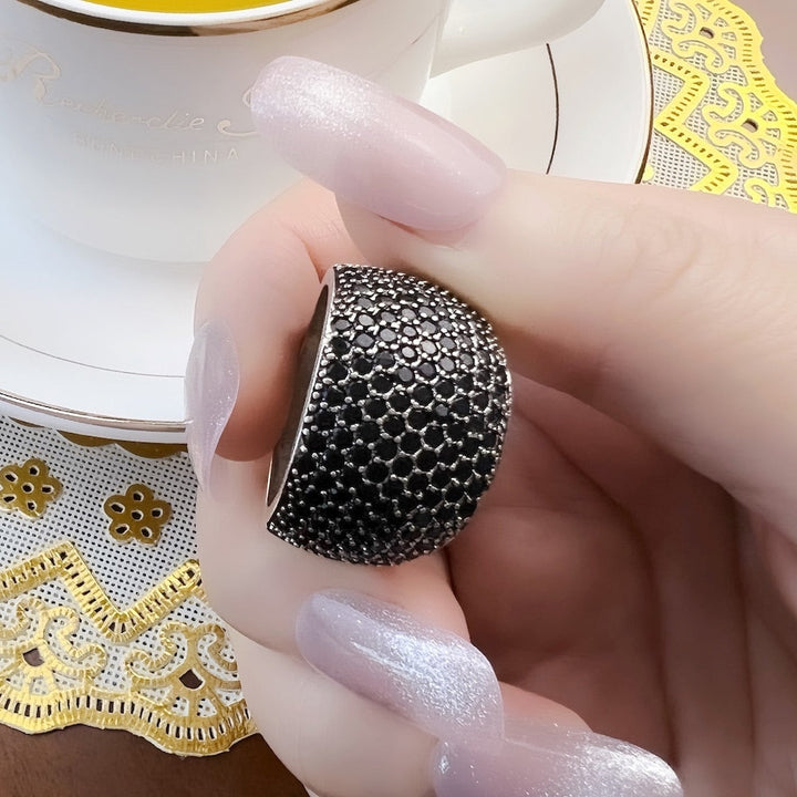Eleganter Unisex-Cocktailring, schwarz mit edlen Pavé-Edelsteinen in glänzender Silberfassung, luxuriöser Schmuck.