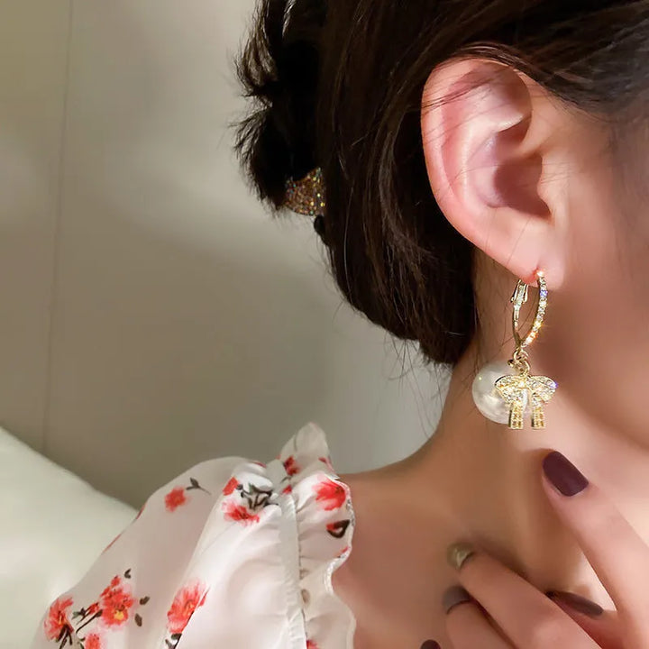 Festliche Tropfenohrringe für Damen: Perlen & rote Schleifen für einen glamourösen Weihnachtslook.