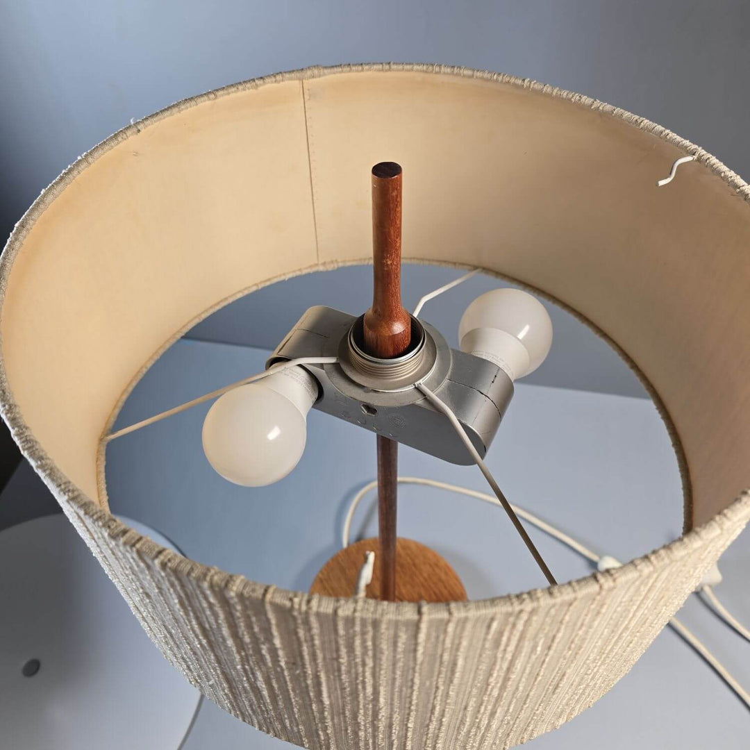 Detailaufnahme des Teakholzfußes einer Mid-Century Tischlampe; natürliche Holzmaserung als Designelement.