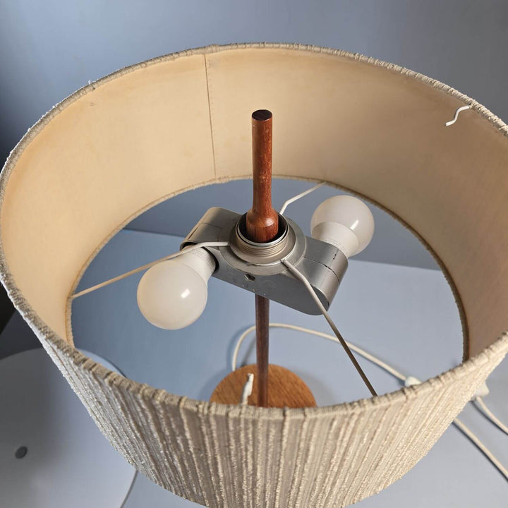 Detailaufnahme des Teakholzfußes einer Mid-Century Tischlampe; natürliche Holzmaserung als Designelement.