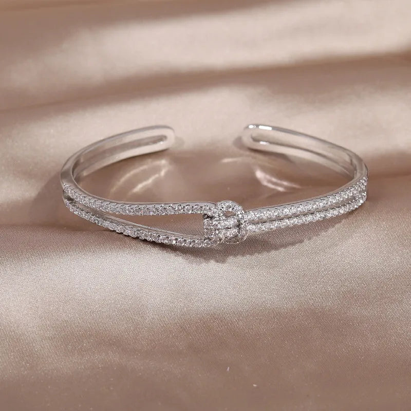 Glänzender Damen Schmuck Armreifen mit strahlenden Kristallen und filigranem Goldknoten.