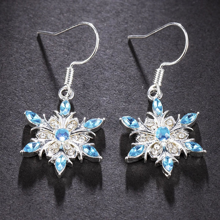 Elegante Damen-Ohrringe im Schneeflocken-Stil mit funkelnden blauen Strasssteinen. Winterschmuck.