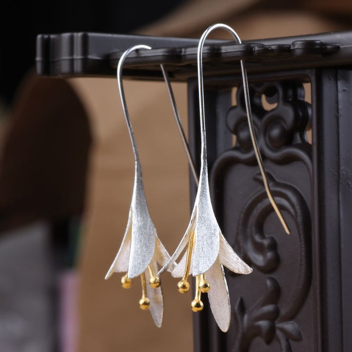 Detailaufnahme eleganter langer Blumenohrringe aus glänzendem 925er Sterlingsilber.