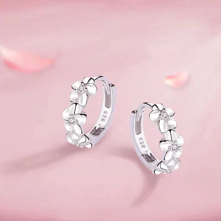 Nahaufnahme von zarten Silber Blumenohrringen mit detailreichen Anhängern, ideal als elegantes Accessoire.