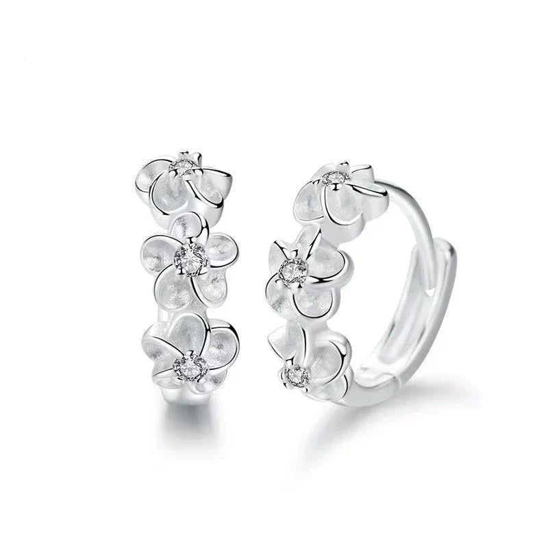 Filigrane Sterlingsilber Damenohrringe mit verspielten Blumenanhängern, die Eleganz und Freude verleihen.