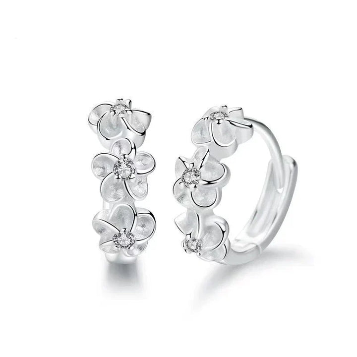 Filigrane Sterlingsilber Damenohrringe mit verspielten Blumenanhängern, die Eleganz und Freude verleihen.