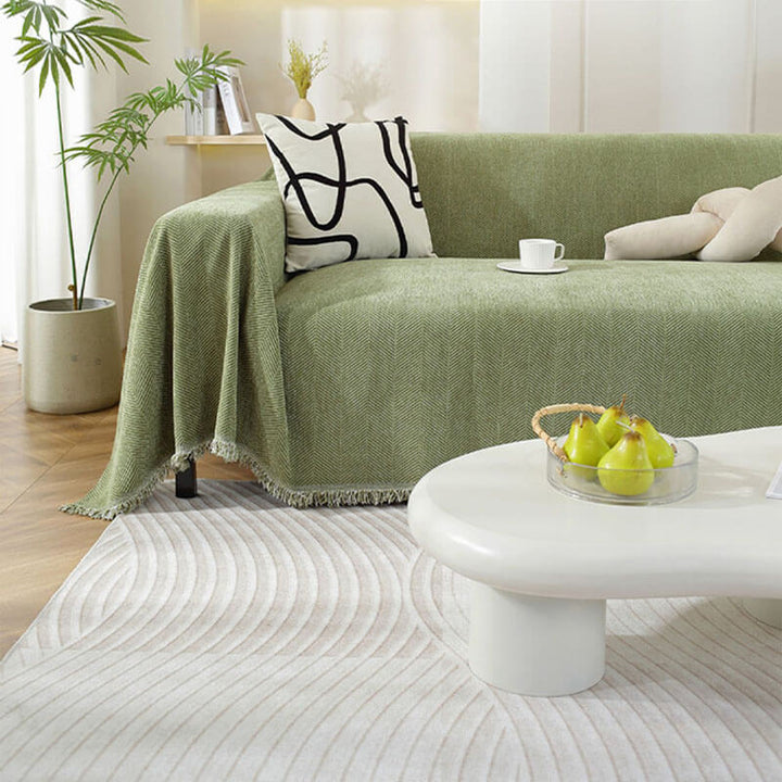 Stilvoller Chenille Sofabezug als moderne Heimtextilie mit Fischgrätenmuster & Quastenakzenten.