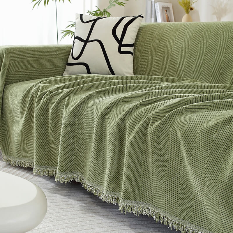 Chenille Sofabezug mit Fischgrätenmuster & Quasten, elegant auf einem Wohnzimmersofa.