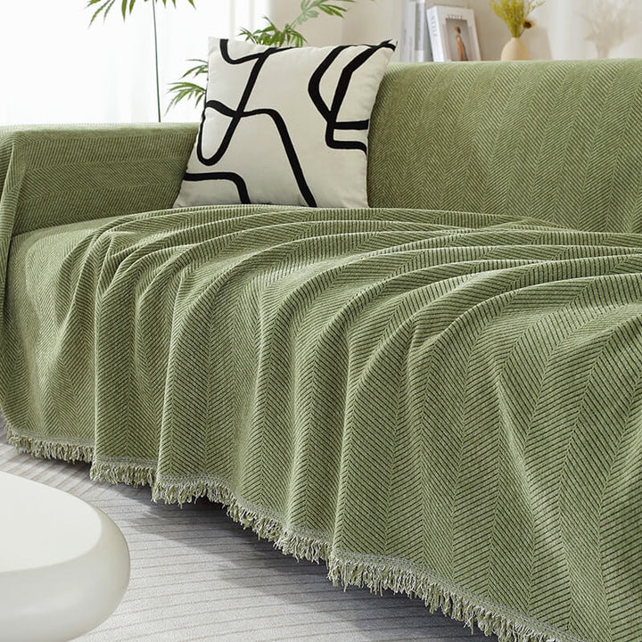Chenille Sofabezug mit Fischgrätenmuster & Quasten, elegant auf einem Wohnzimmersofa.