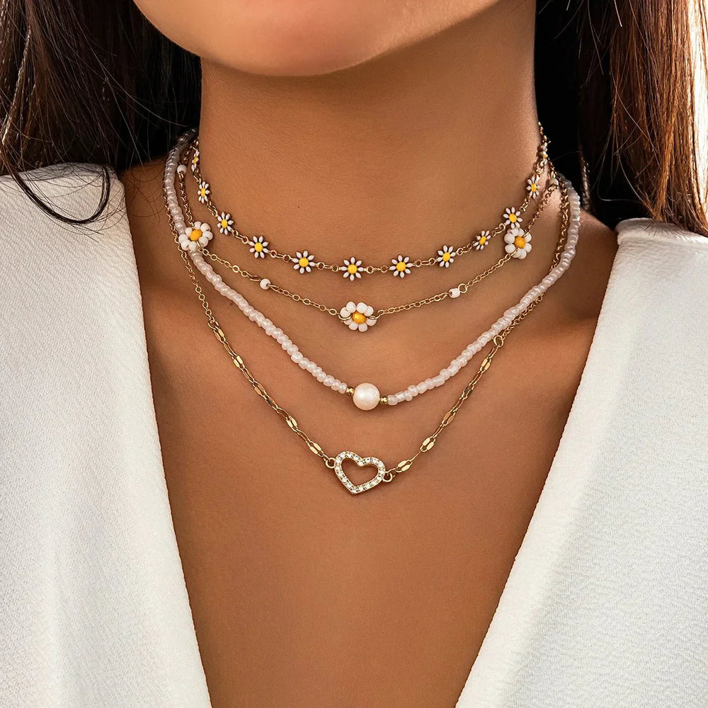 Mehrreihiges Damen Schmuckset: Boho Ketten mit Gänseblümchen-Anhängern und zarten Perlen.