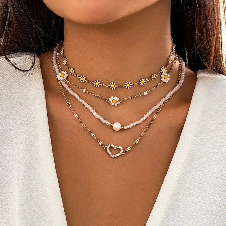 Mehrreihiges Damen Schmuckset: Boho Ketten mit Gänseblümchen-Anhängern und zarten Perlen.