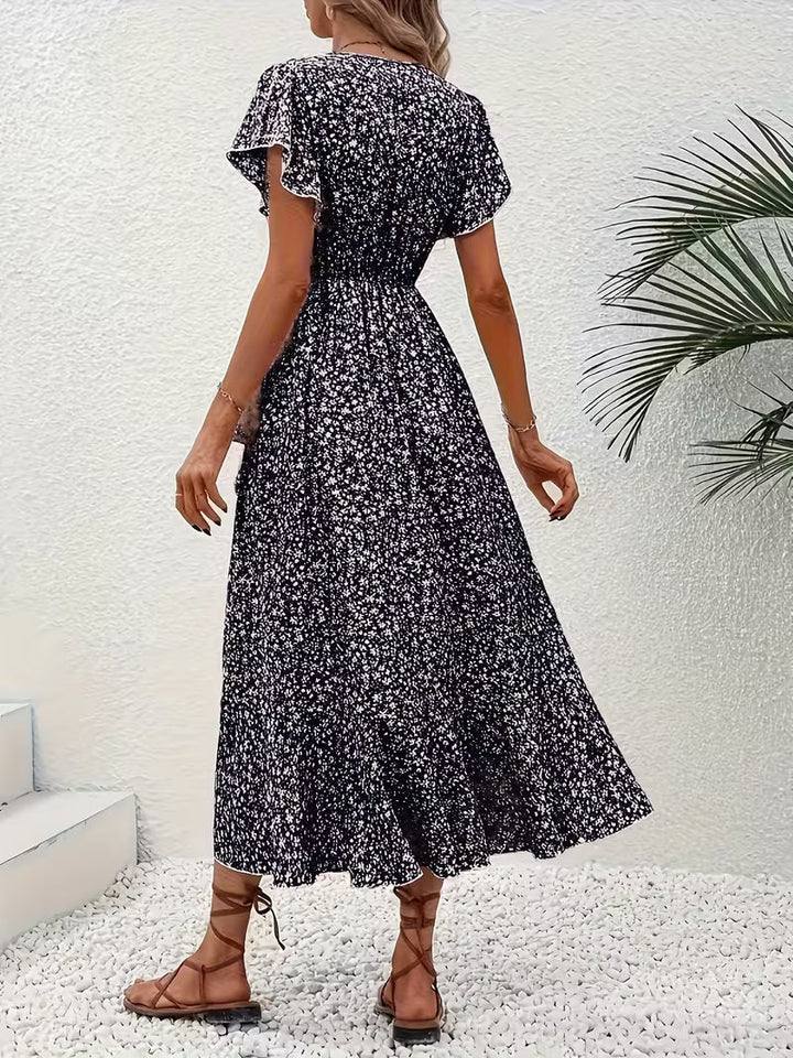 Frau im fließenden Sommerkleid sitzt auf einer Parkbank, bauchumspielendes Wickelkleid.