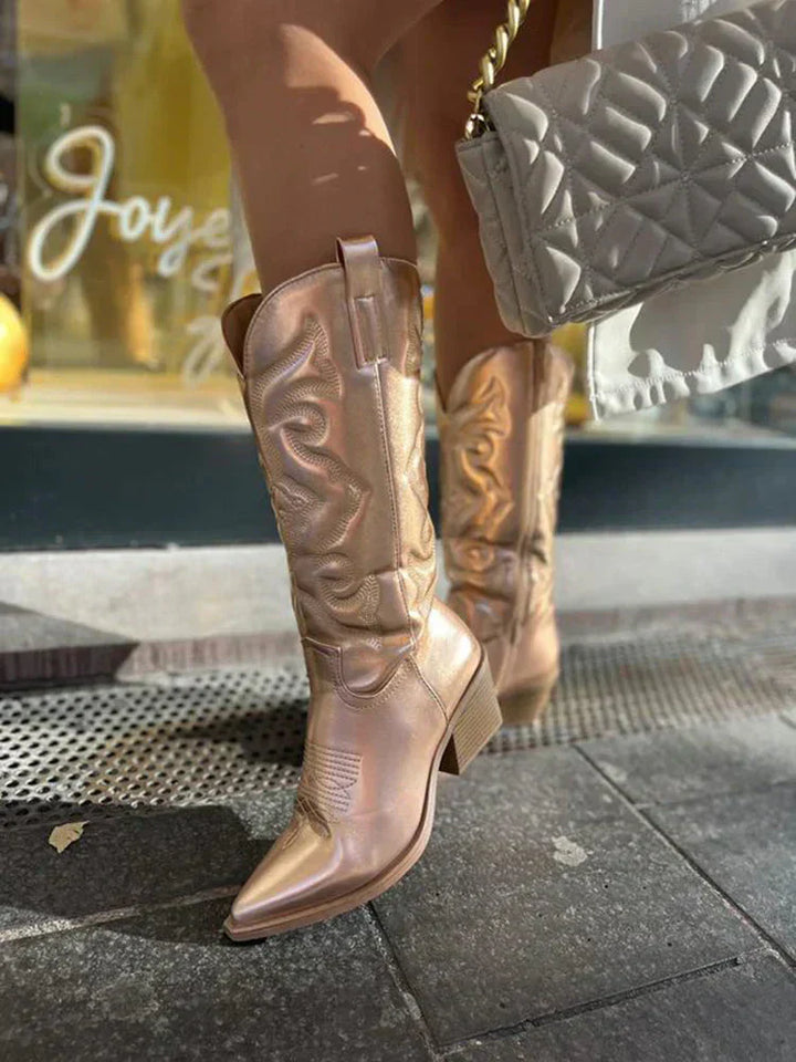 Model trägt funkelnde Metallic Cowboystiefel, die den Western-Stil perfekt ergänzen. Modische Damenschuhe.