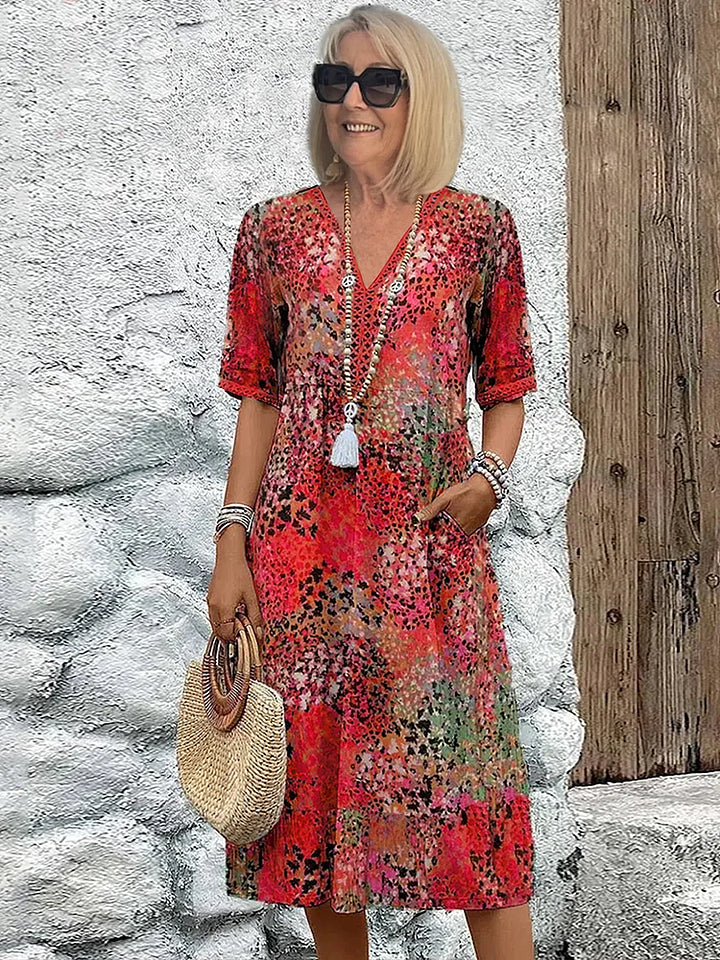 Detailaufnahme: V-Ausschnitt und lebendige Prints auf einem sommerlichen Damen Midi-Kleid. Elegant & bequem.