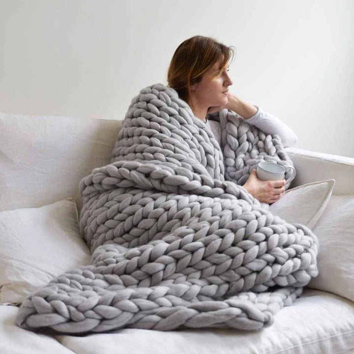 DIY Chunky XL Wollgarn auf einem Sofa, lädt zum Stricken einer kuscheligen Decke für gemütliche Abende ein.