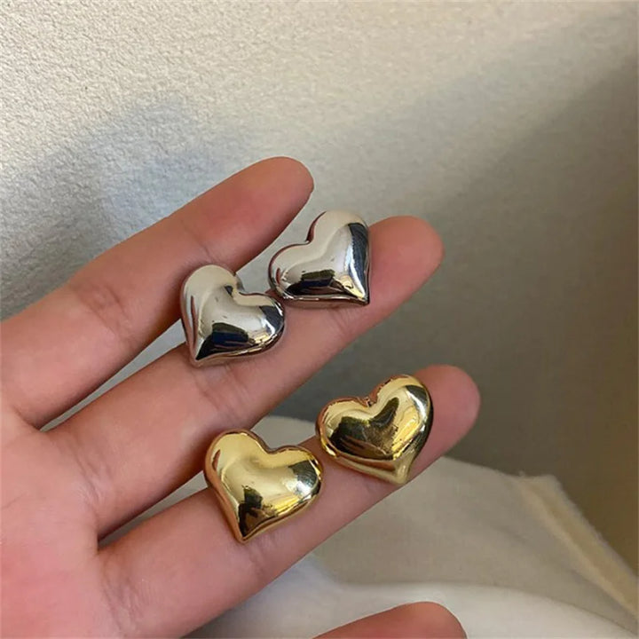 Nahaufnahme der zarten Herzohrringe für Damen, gefertigt aus strahlendem Gold und schimmerndem Silber.