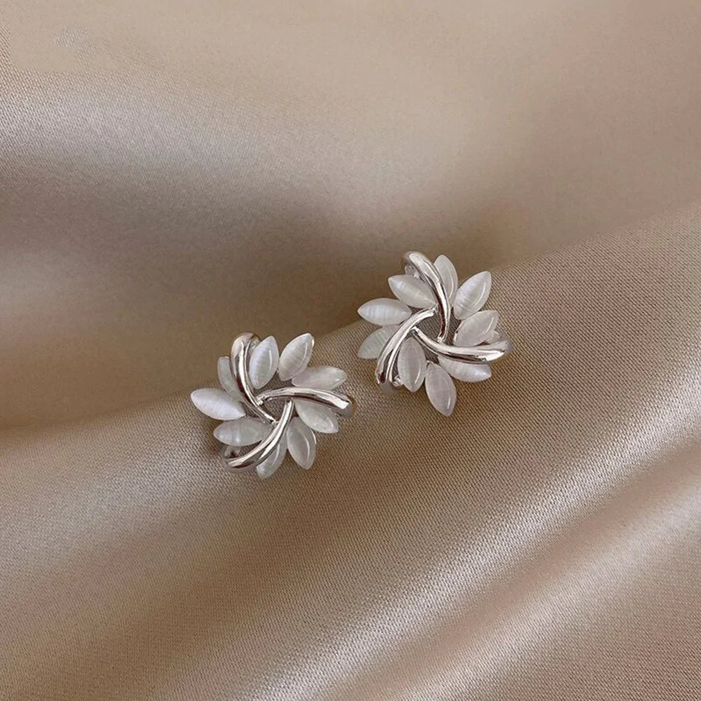 Detailaufnahme von runden Opal-Blumen-Ohrsteckern. Schillernder Opal und zartes Blumen-Design als Damenschmuck.