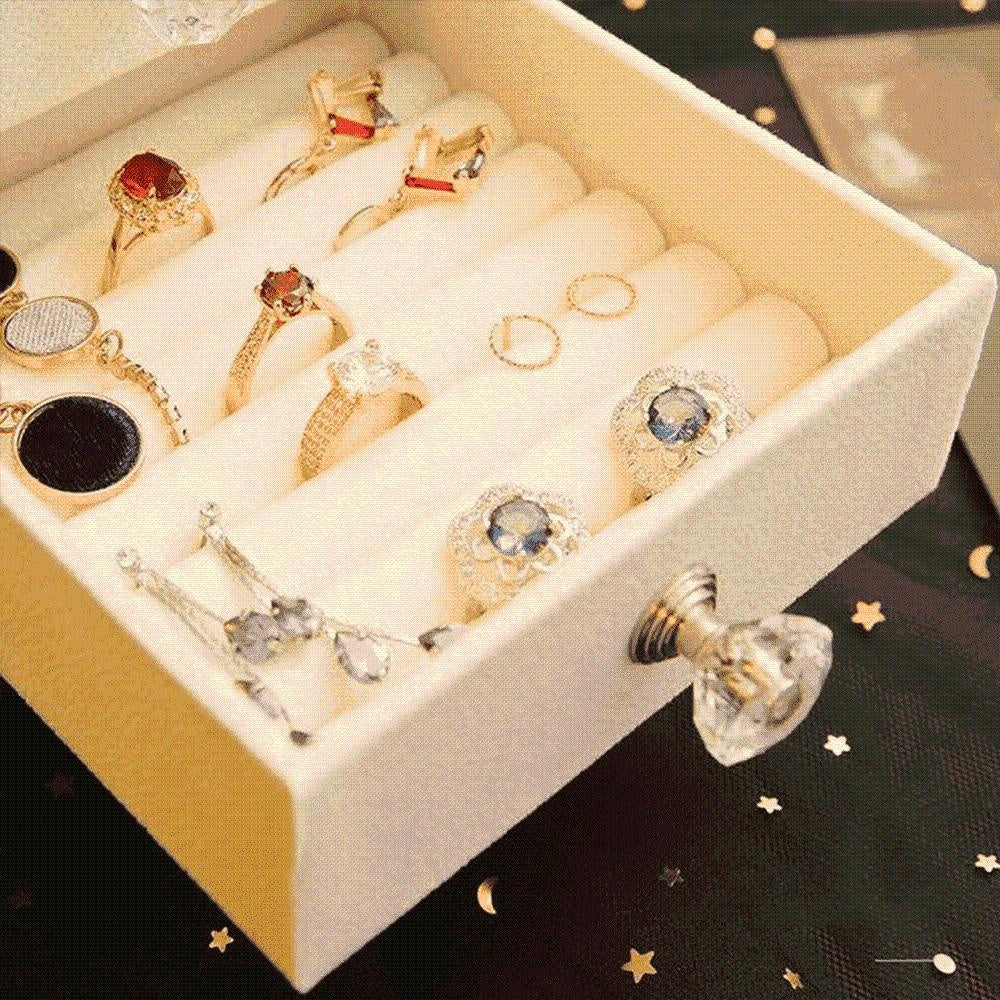 Nahaufnahme der Schmuckbox mit organisiertem Schmuck: Ringe, Ohrringe, Armbänder in Fächern.