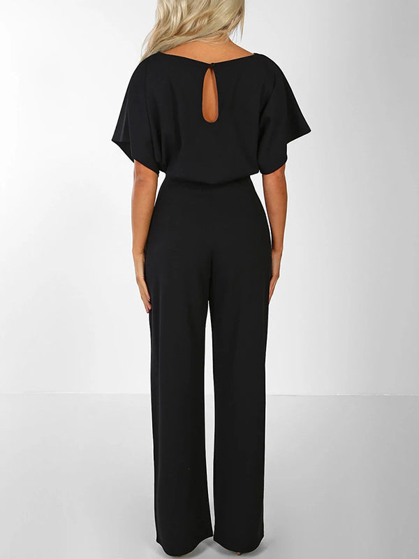 Model sitzt im bequemen blauen Damen Jumpsuit mit Rüschengürtel & kurzen Ärmeln, Freizeitmode.