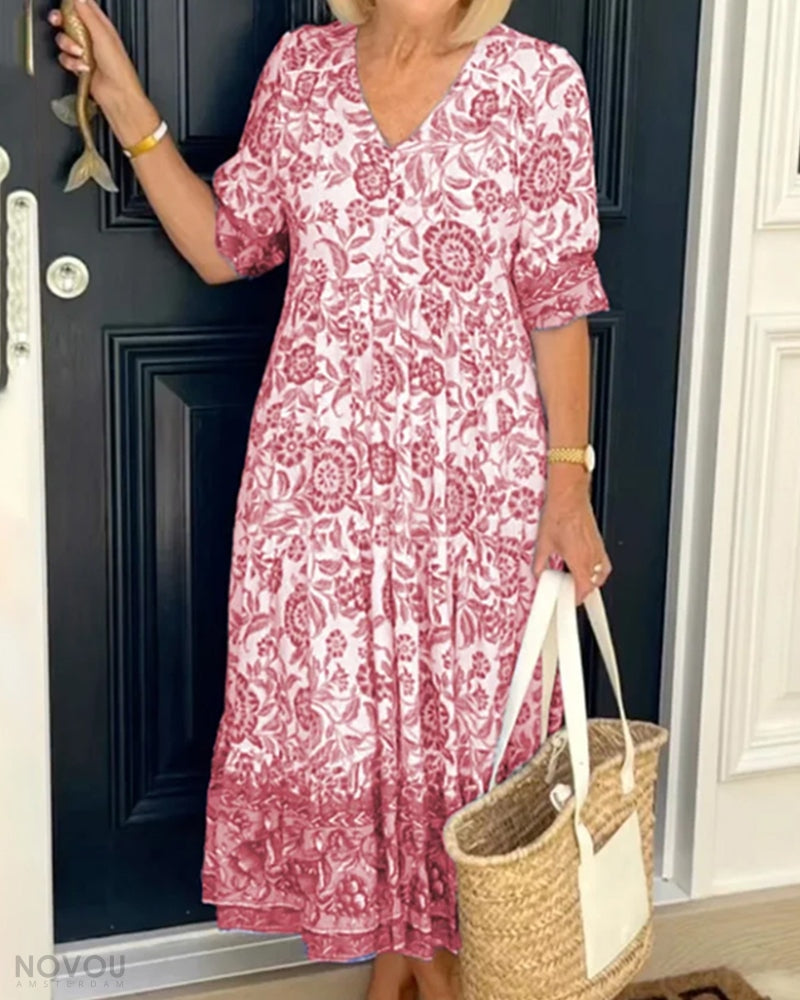 Frau trägt elegantes, tailliertes Blumenkleid, knielang mit V-Ausschnitt. Ideales Damen Sommerkleid.