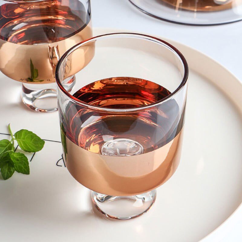 Nordische Trinkgläser aus rauchgrauem Glas mit Roségold-Akzenten. Ergänzen Karaffe ideal.
