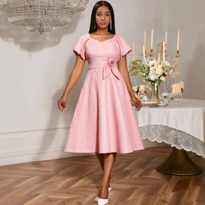 Elegantes rosa Damenkleid mit Puffärmeln und Schleife, ideal für festliche Anlässe und Hochzeitsgäste.
