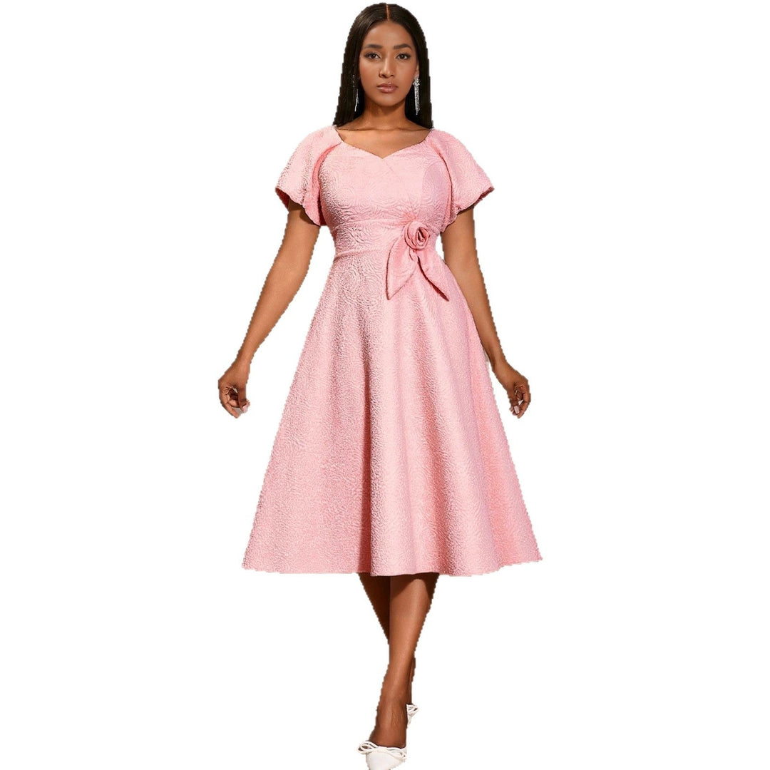 Rosafarbenes Damenkleid mit stilvollen Puffärmeln und einer raffinierten Schleife, perfekt für einen femininen Auftritt.