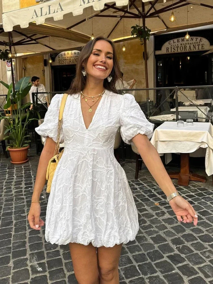 Model trägt weißes Damenkleid mit Rüschen, vielseitig kombinierbar für elegante Anlässe.