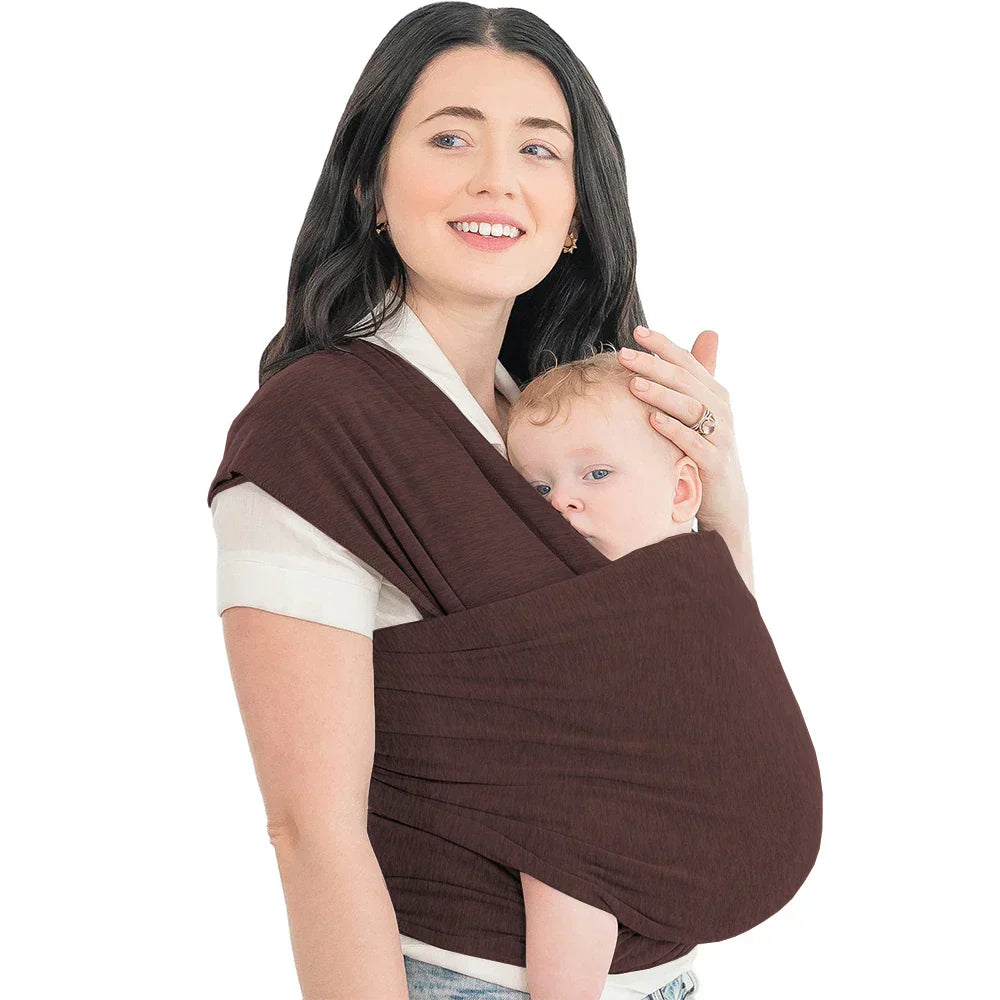 Glückliche Eltern tragen ihr Baby in der CuddleWrap Babytrage mit ergonomischer Rückenunterstützung.