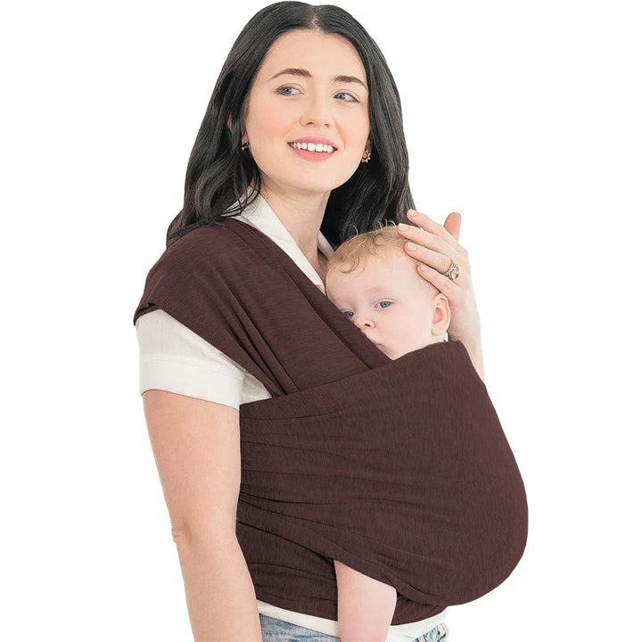 Glückliche Eltern tragen ihr Baby in der CuddleWrap Babytrage mit ergonomischer Rückenunterstützung.