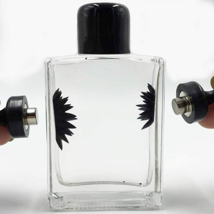 Ferrofluid Display mit Magnet: Dunkles Ferrofluid bildet Spikes unter dem Einfluss eines starken Magneten.