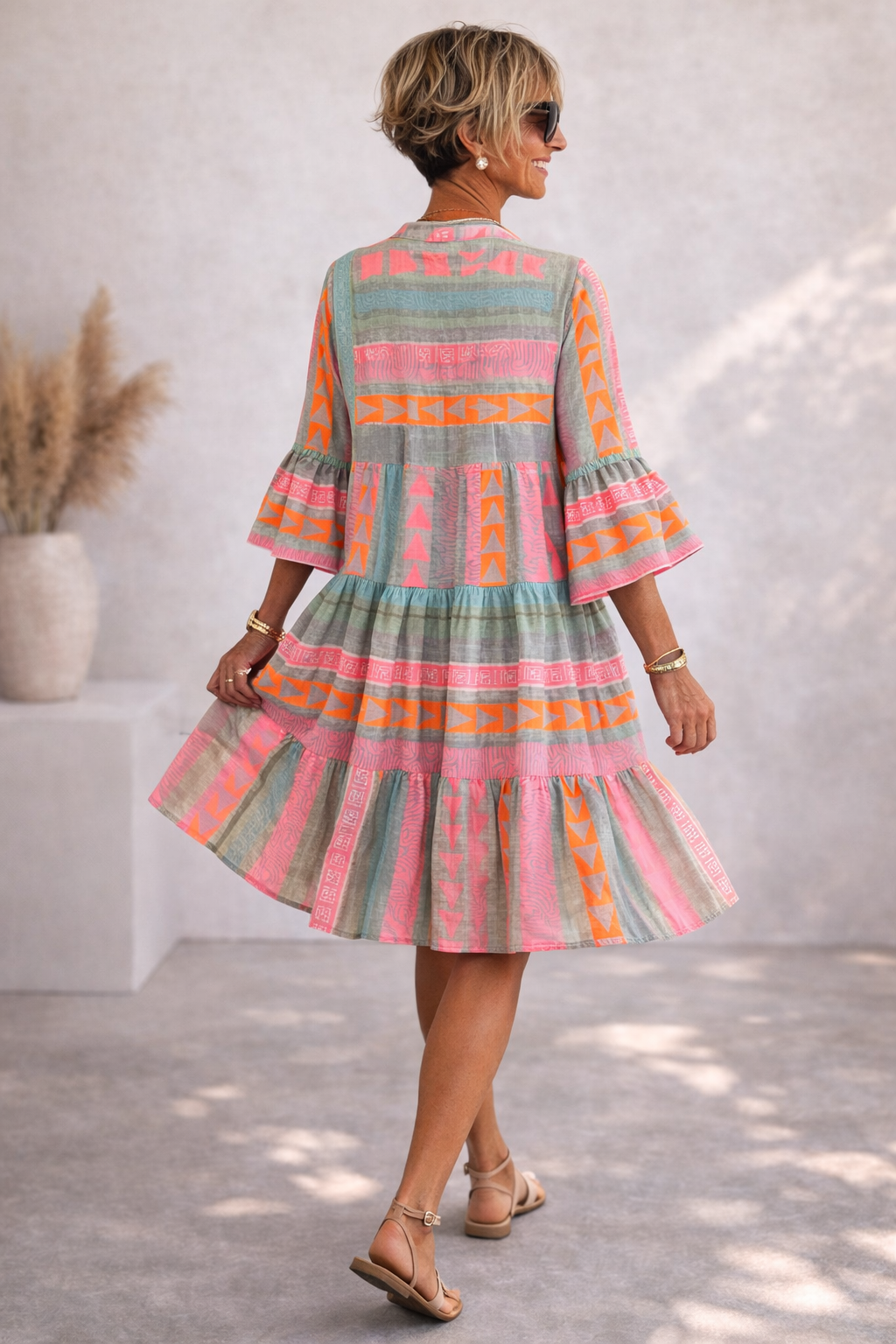 Rosa Damen Midi-Kleid mit elegantem, geometrischem Muster und fließendem Stoff. Ein gemustertes Sommerkleid mit Rüschendetails.