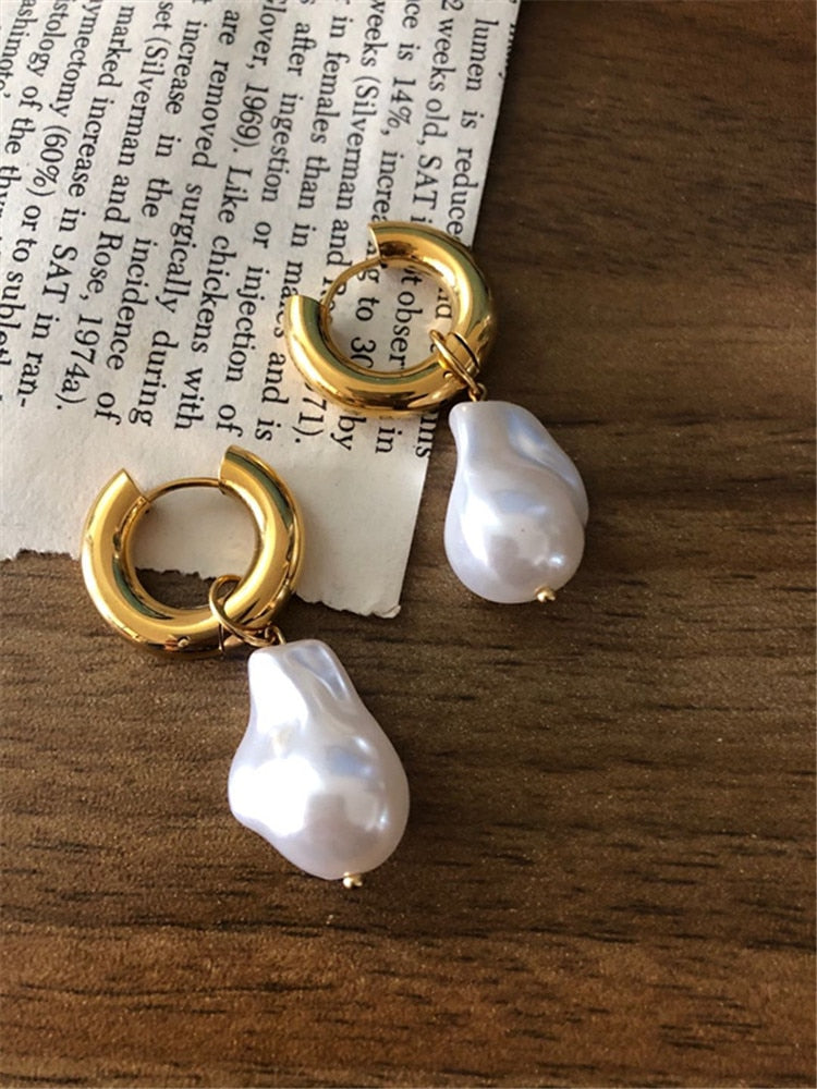 Detailaufnahme: Goldfarbene Vintage Kreisohrringe mit schimmernden Barockperlen. Eleganter Damenschmuck.